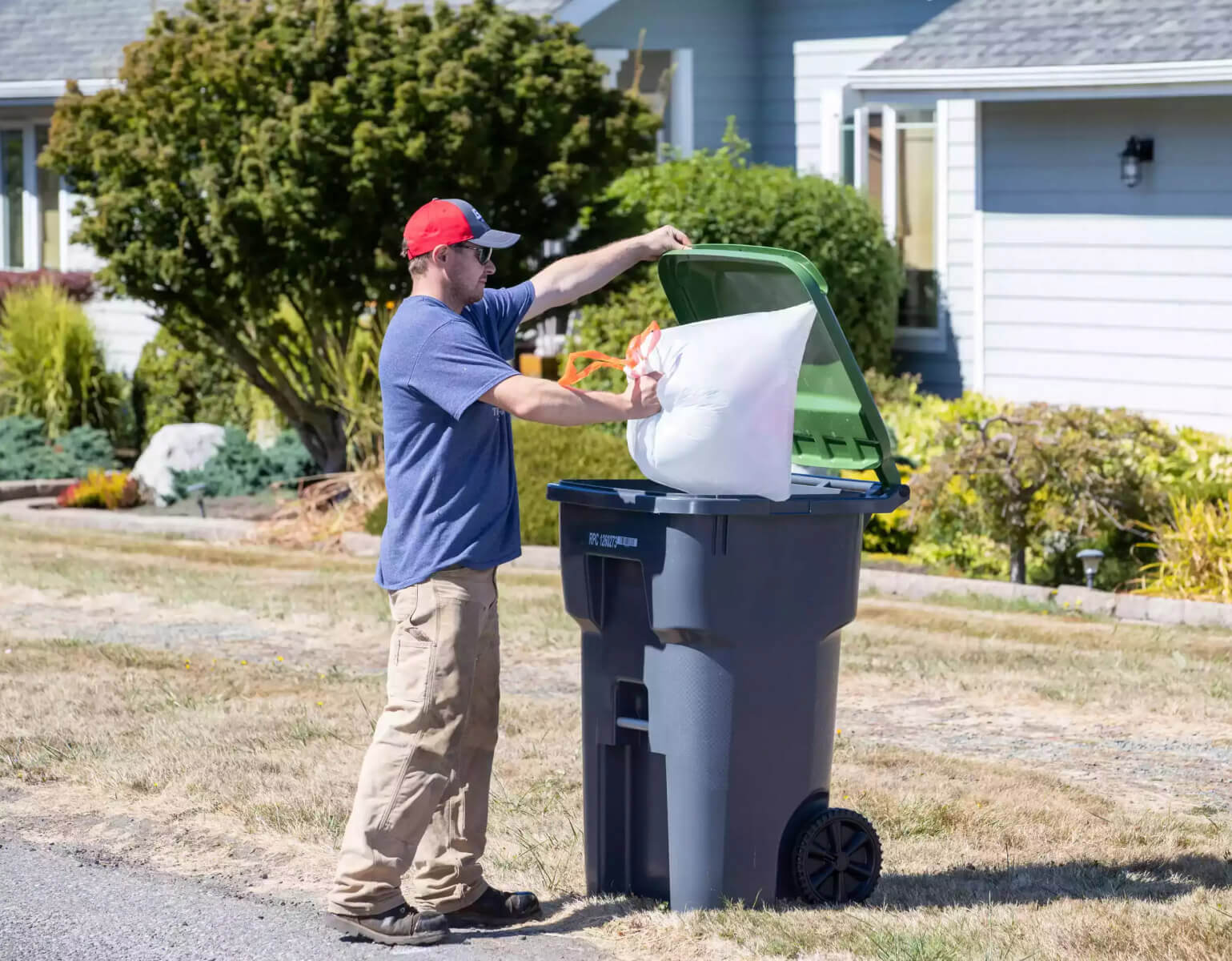 A man throwing a garbage bag in the garbage bin.
